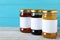 Jars of organic honey with blank labels on table against light blue background. Space for text