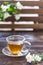 Jasmine tea in transparent cup and jasmine flowers on wooden background. Copy space