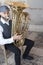 A jazz musician dressed in vintage style, playing the tuba on the street