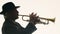 Jazzman in hat and suit plays music on trumpet in studio on white background, side view. Man plays piece at trumpet