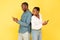 Jealous African American Wife Peeking At Husband's Smartphone, Yellow Background