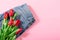 Jeans and bouquet of red tulips on pink background with copy space, empty text place. Advertising banner of fashionable casual