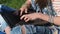 Jeans and a laptop. Hands of a teenager in bracelets print on a laptop. Ragged jeans.