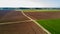 A jeep crossing a country road, off-road aerial view of a car traveling a dirt road through the fields.