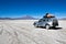 Jeep in the landscape of the Salar de Uyuni and lagoons like Lag