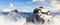 Jeep on top of snowy rock peak with mountain landscape in background