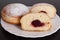 Jelly filled doughnuts on white plate on black wooden background