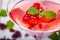 Jelly with red currant in martini glass on wooden background.