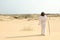 Jesus Christ walking with stick in desert, back view. Space for text