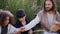 Jesus gives bread to children while sitting among the grass on the hill.