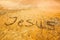 Jesus, written on a sandy beach.