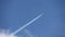 Jet airliner flying out of clouds in the sky leaves contrails