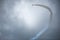 Jet airplane making a curve with white smoke against a dark sky