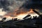 Jet fighter pilots sat in row of war planes squadron on runway at sunset getting ready to take off. Dramatic red fire sun sky