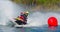 Jet Ski racer cornering around buoy at speed creating at lot of spray.