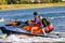 Jet ski watercraft driver with delighted woman on back seat in action on summer sunny day