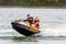 Jet ski watercraft driver with joyful woman on back seat in action on summer sunny day