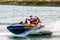 Jet ski watercraft driver with joyful woman on back seat in action on summer sunny day