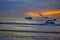 Jet skis and leisure boat parked on the sea in a reddish sunset with cloudy sky