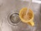 A jet of water filling a yellow mug with water in an iron gray sink