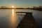 Jetty on a frozen lake, sunshine glow on the sky, winter view