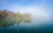 Jetty at the lake in the fog. Misty landscape in the morning. Idyllic nature by the water.