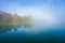 Jetty at the lake in the fog. Misty landscape in the morning. Idyllic nature by the water.