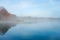 Jetty at the lake in the fog. Misty landscape in the morning. Idyllic nature by the water.