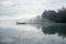 Jetty at the lake in the fog. Misty landscape in the morning. Idyllic nature by the water.