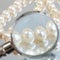 Jeweler looking at pearls necklace through magnifying glass, jewerly inspect and verify, pawnshop concept