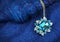 Jewelry pendant with gems on dark blue sand background