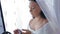 A Jewish bride in a dress and veil in front of a mirror applies makeup before the chuppah ceremony