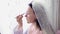 A Jewish bride in a room in front of a mirror applies makeup before the chuppah ceremony, reflected in the mirror