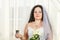 Jewish bride with a veil before the chuppa ceremony with a bouquet of white roses in her hands and a glass of wine.