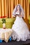 Jewish bride in a white dress, veiled face at a table with flowers, reads a prayer before the hupa ceremony.