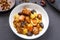 Jewish cuisine dish sweet tsimes with dates, carrots and turkey meat in a white plate on a black board on a concrete background