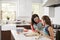 Jewish girl glazing plaited challah bread dough with her mum