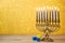 Jewish holiday Hanukkah background with vintage menorah and spinning top dreidel over lights bokeh.