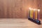 Jewish Holiday Hanukkah menorah with colorful candles over wooden background