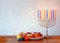 Jewish holiday Hanukkah with menorah, doughnuts over wooden table. retro filtered image