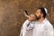 Jewish man blowing shofar on Rosh Hashanah outdoors. Wearing tallit with words Blessed Are You, Lord Our God, King Of The Universe