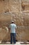 A Jewish man dressed in casual modern clothing prays at the Western Wall