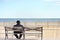 Jewish man sitting on bench near ocean