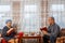 A Jewish married couple in headdresses at home at the table, a man writes in a notebook, his wife knits on knitting