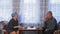 A Jewish married couple in traditional headdresses are arguing at a table in a room