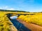 Jizerka stream on green meadow with old small stone bridge, Jizerka village, Jizera Mountains, Czech Republic