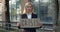 Jobless female worker in 30s standing at street and looking to camera. Unhappy woman in suit holding carton banner with