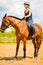 Jockey girl doing horse riding on countryside meadow