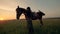 Jockey girl is getting down from her horse and caressing it in the open air