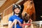 Jockey girl putting halter on her bay horse muzzle